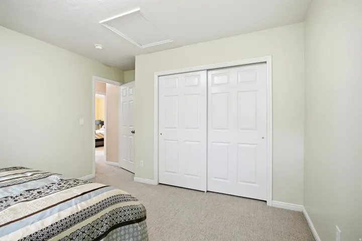 Spacious secondary bedroom featuring neutral wall finishes, neutral-tone carpet flooring, and dual sliding closet doors with six-panel design