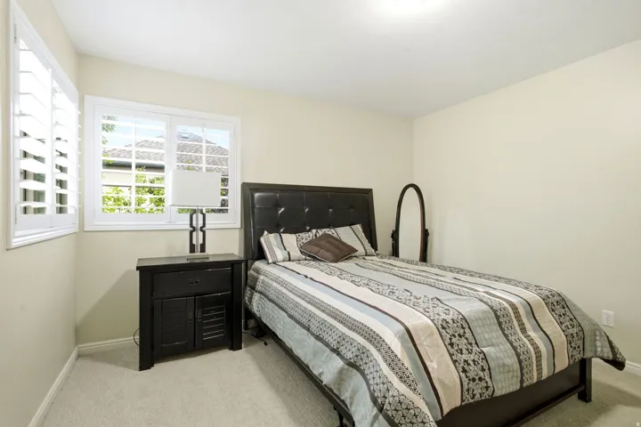 Dual windows with white plantation shutters, neutral wall color, and light-toned carpeting