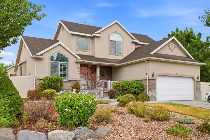Elegant two-story residence featuring a stucco exterior with stone accents, multi-pane windows, and a covered front porch