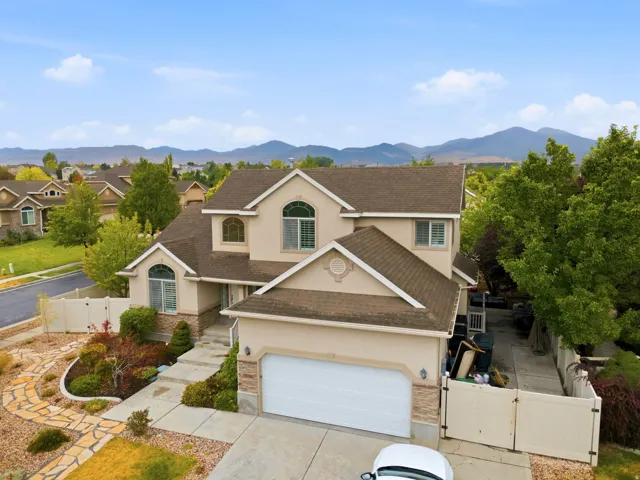 Stucco exterior with stone accents, arched windows, an attached garage, and a flagstone pathway