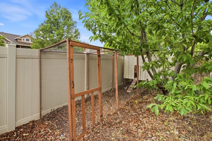 Secure backyard retreat featuring a wood-frame enclosure with mesh screening, gravel ground cover, and mature shade trees