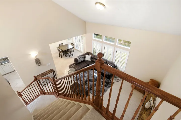 Carpeted staircase with wood banister, vaulted ceiling, and recessed lighting