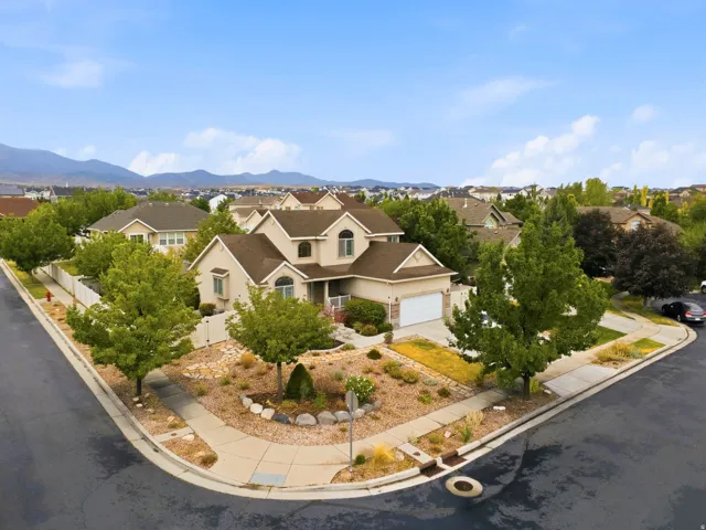 Two-story residence featuring a two-car garage, mature landscaping, and a corner lot