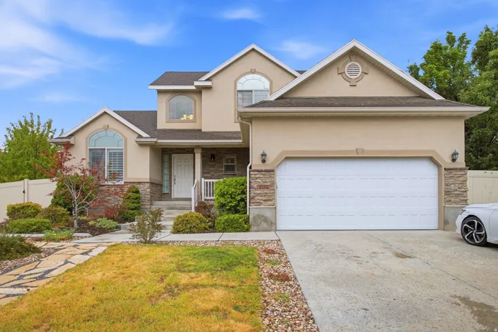 Elegant two-story residence featuring a stucco exterior with stone accents, arched entryway, and multi-pane windows
