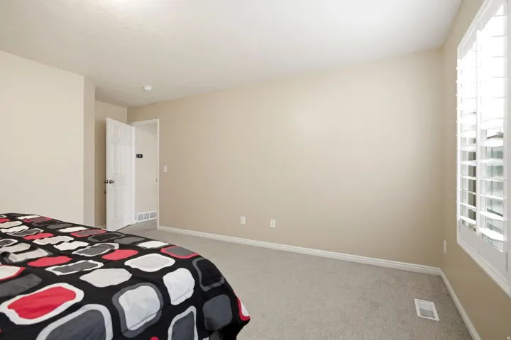Bright secondary bedroom with neutral wall finishes, recessed ceiling lighting, and large multi-pane windows providing natural light