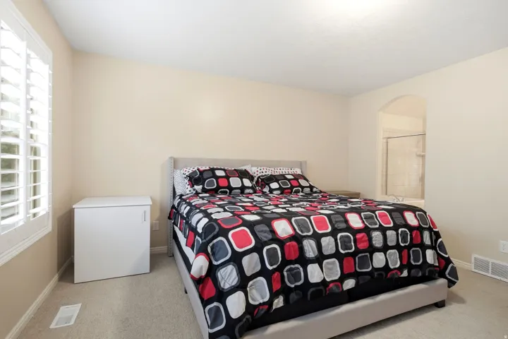 Carpeted flooring, recessed ceiling lighting, arched doorway, and plantation shutters
