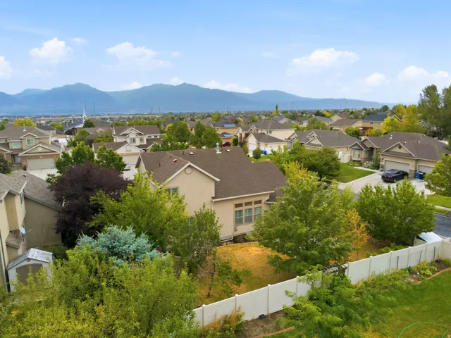 Expansive neighborhood setting with distant mountains, featuring mature trees and a privacy fence