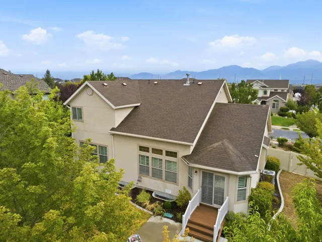 Elegant two-story residence featuring a steeply pitched architectural roof design with multiple gables, neutral exterior siding, and dark asphalt shingle roofing