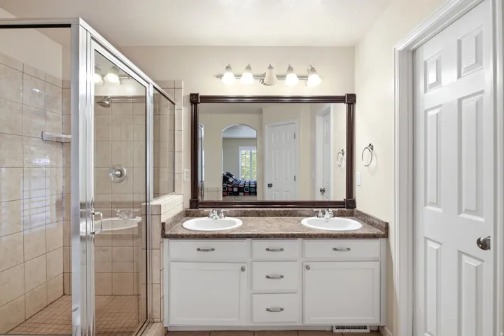 Dual vanity with integrated sinks, framed mirror, and white cabinetry