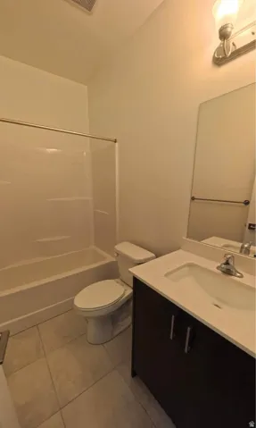 Bathroom featuring a white bathtub, toilet, dark wood-finish vanity with a light countertop, and a wall-mounted mirror