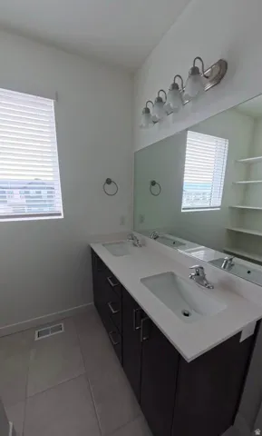 Dual vanity with integrated sinks, light-toned countertop, and dark wood-finish cabinetry
