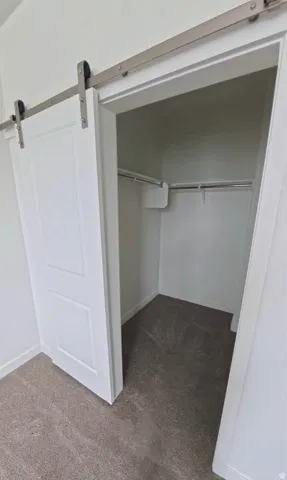 Barn-style door with brushed nickel hardware, built-in closet shelving, and integrated hanging rods