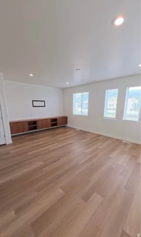 Recessed lighting, wood-finish flooring, multiple windows, built-in cabinetry, and white interior walls