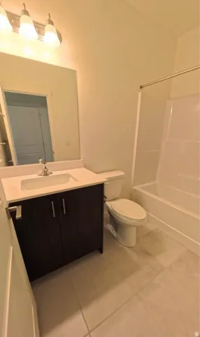 Vanity with integrated sink, modern cabinetry, wall-mounted mirror, overhead lighting fixture, and a tub/shower combination