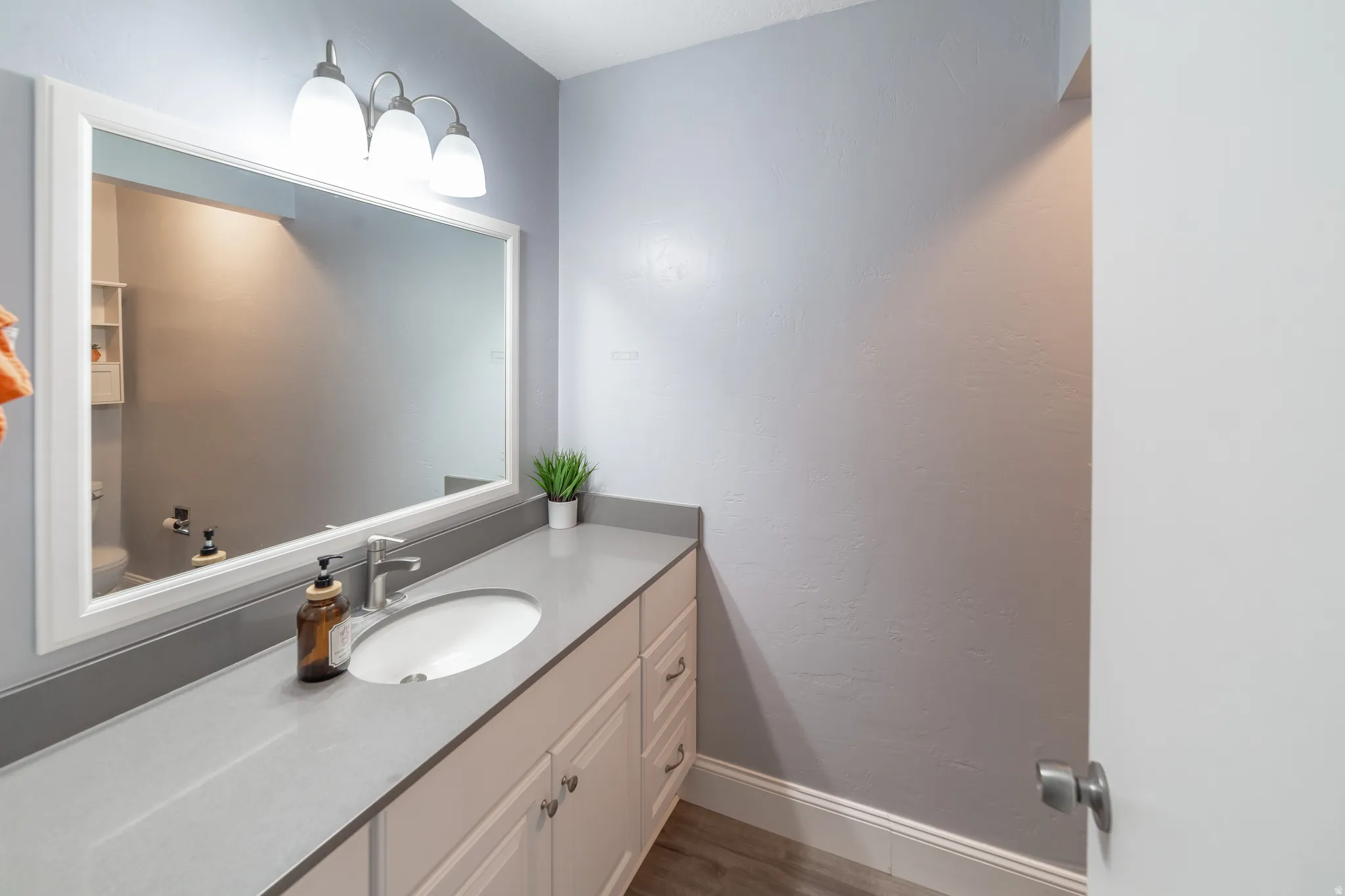 Vanity with an integrated oval sink, brushed nickel faucet, and a large framed mirror