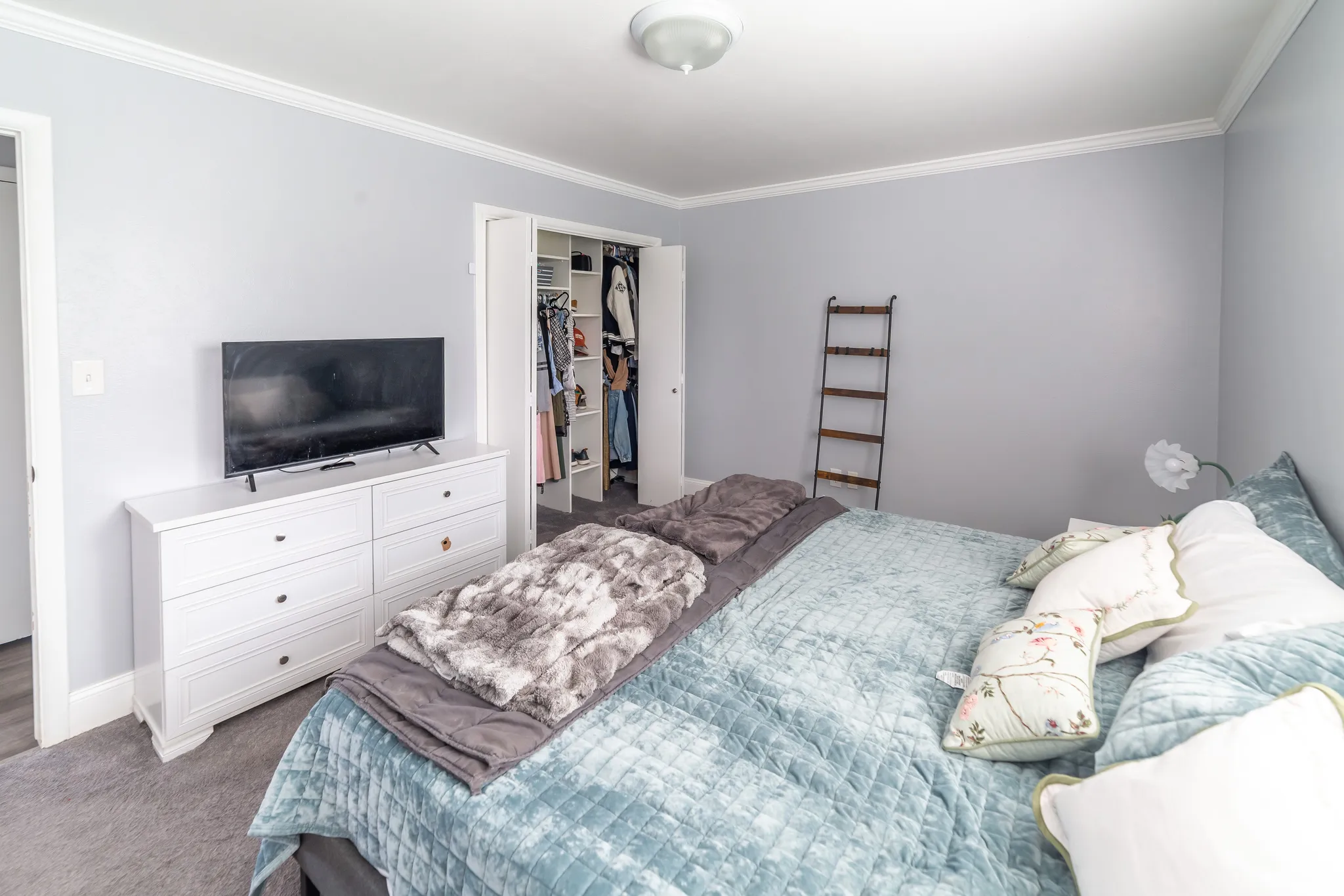 Recessed ceiling light fixture, crown molding, gray wall tones, and gray carpet flooring