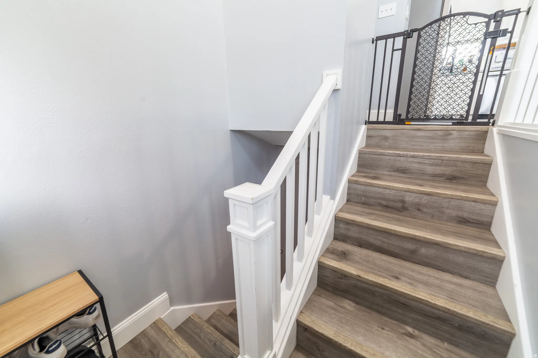 Staircase featuring wood-finish treads and risers, white painted balusters, and a substantial newel post