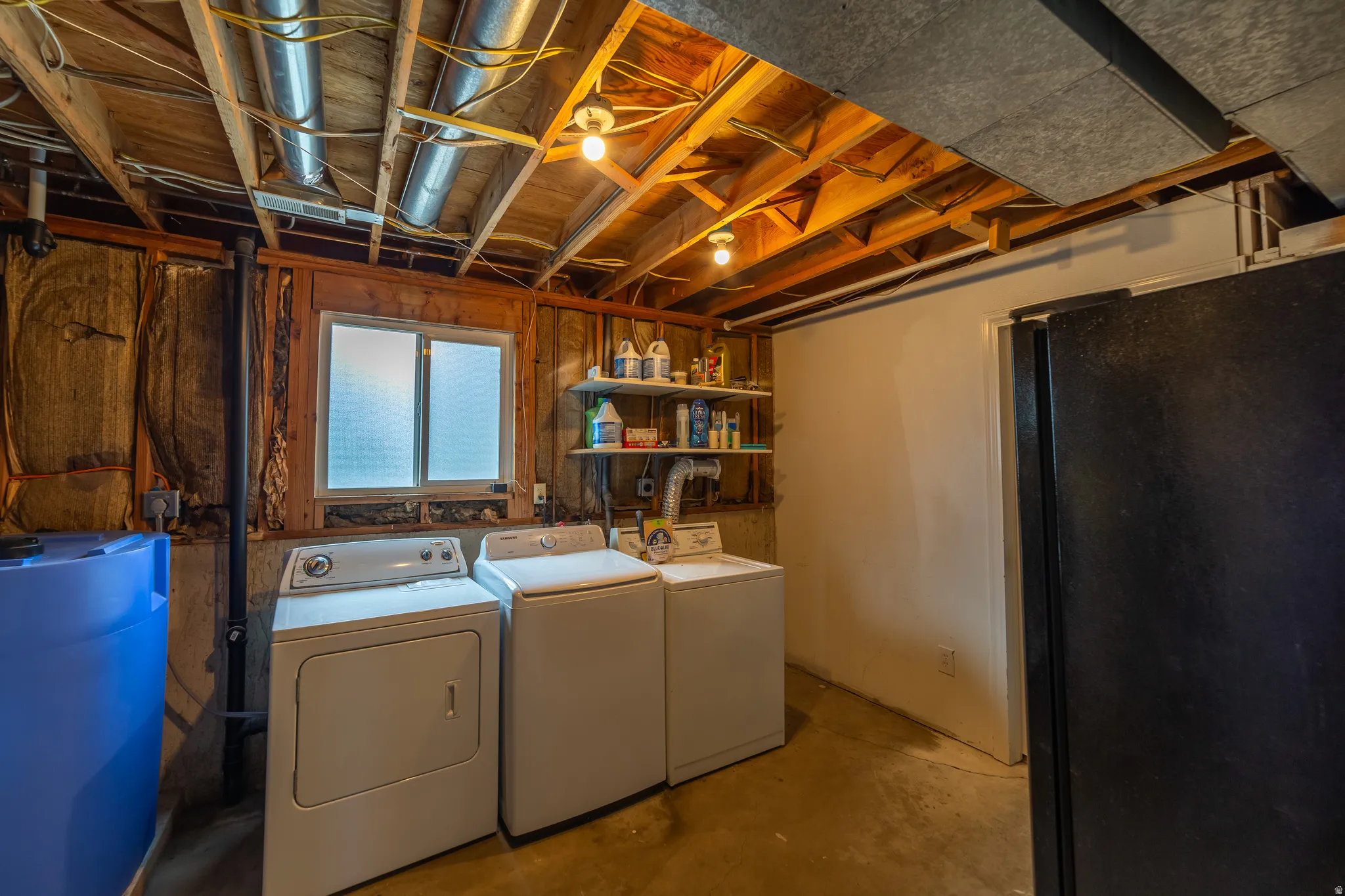 Laundry area with exposed ceiling joists, visible ductwork, and a utility window