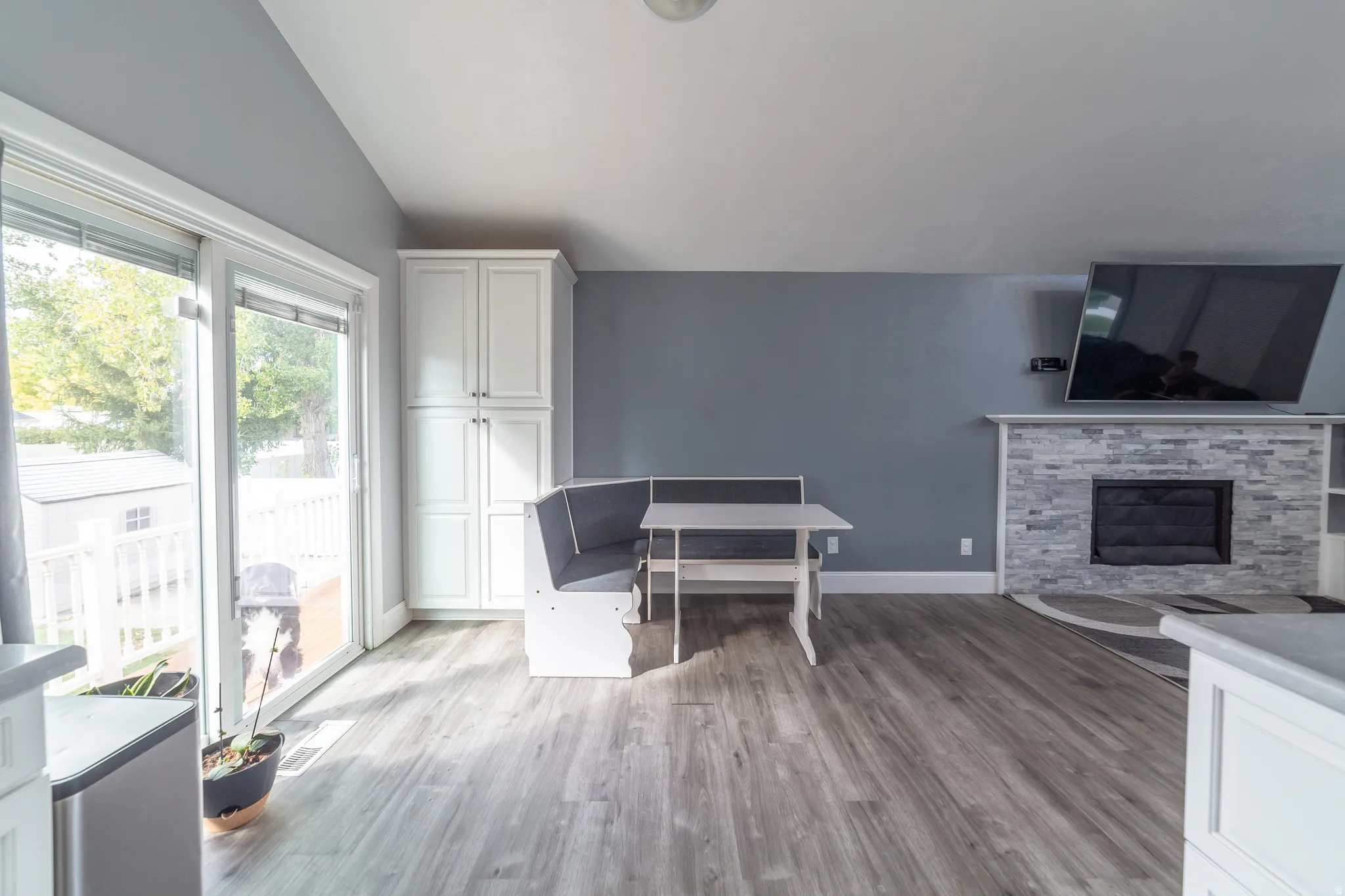 Living area featuring wood-finish flooring, a stone-faced fireplace with white mantel, built-in cabinetry, and a sliding glass door