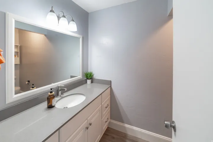 Vanity with an integrated oval sink, brushed nickel faucet, and a large framed mirror