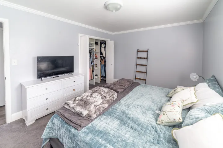 Recessed ceiling light fixture, crown molding, gray wall tones, and gray carpet flooring