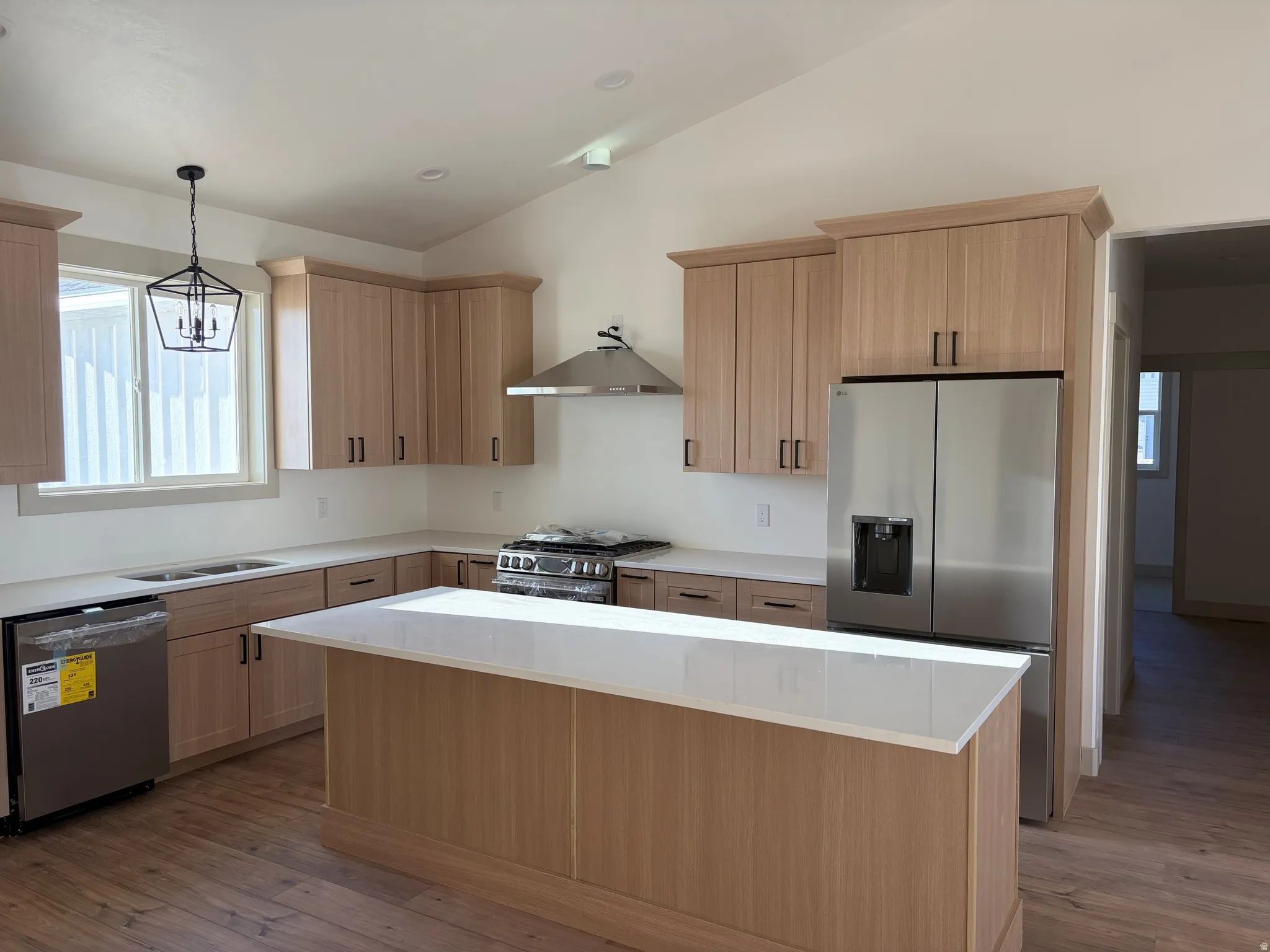Kitchen featuring wood-finish cabinetry, stainless steel appliances, a center island with a white countertop, recessed lighting, and wood-finish flooring