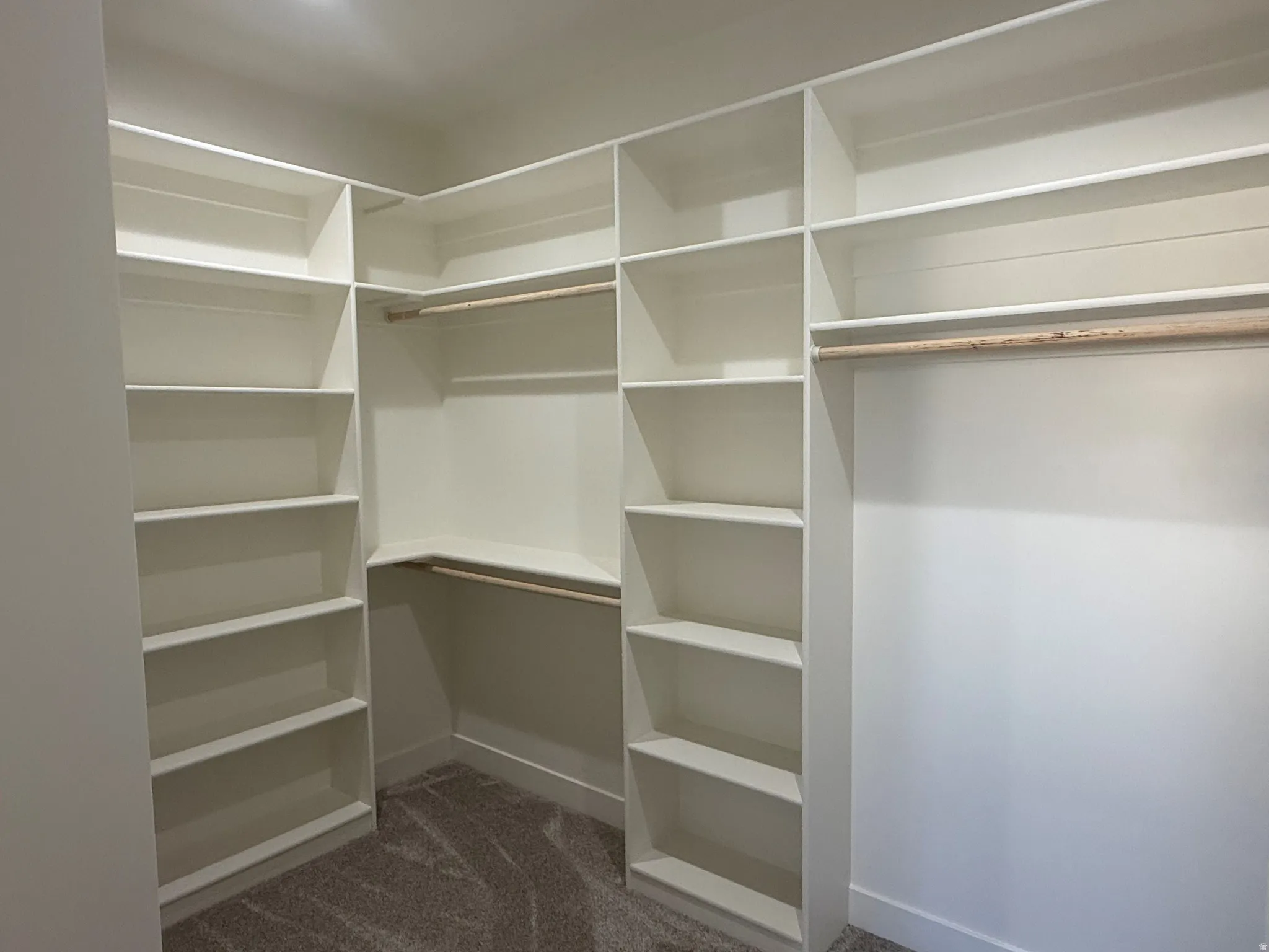 Custom built-in white shelving, integrated hanging rods, and plush carpet flooring