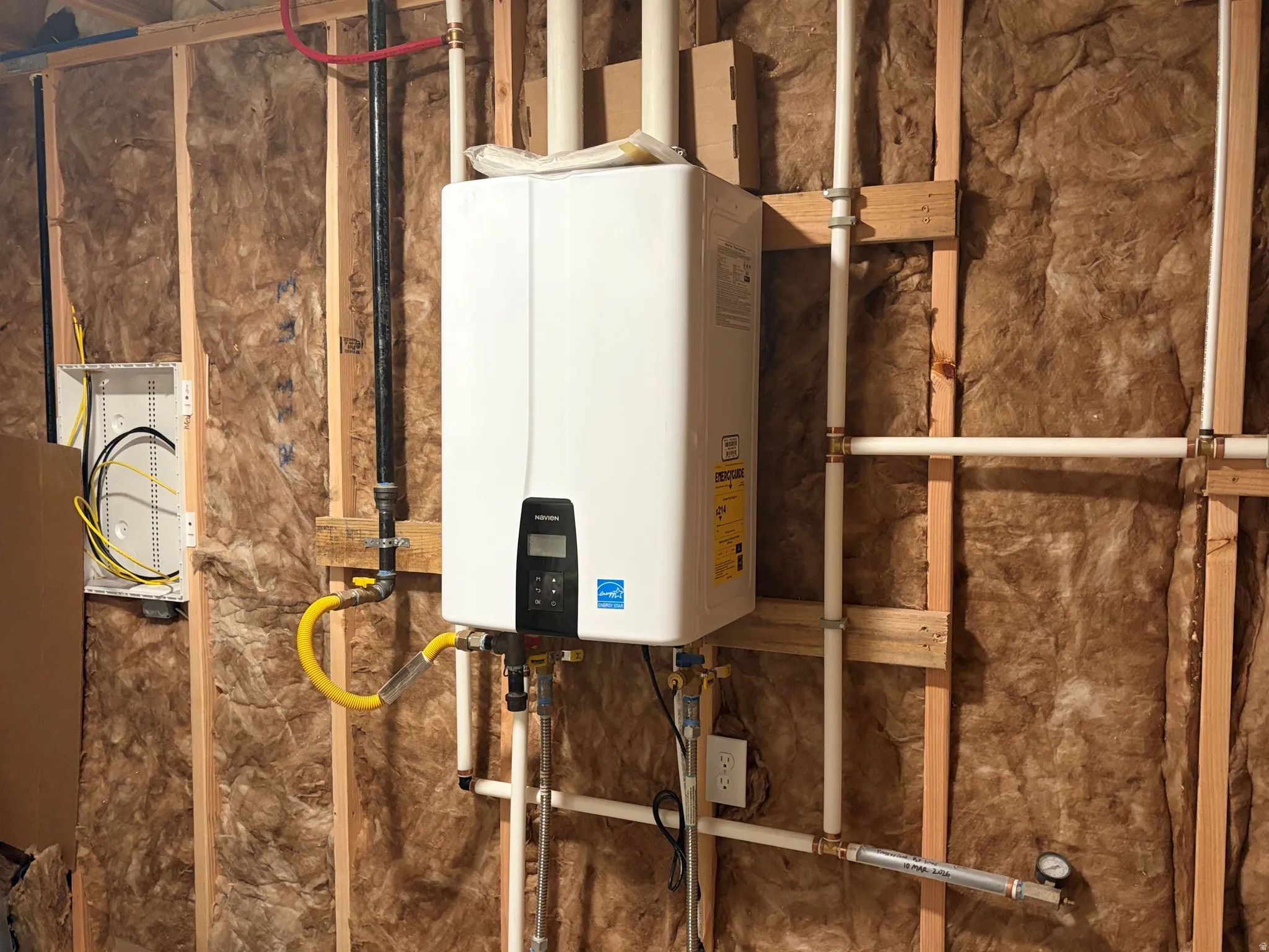 Tankless water heater with visible plumbing and electrical service panel
