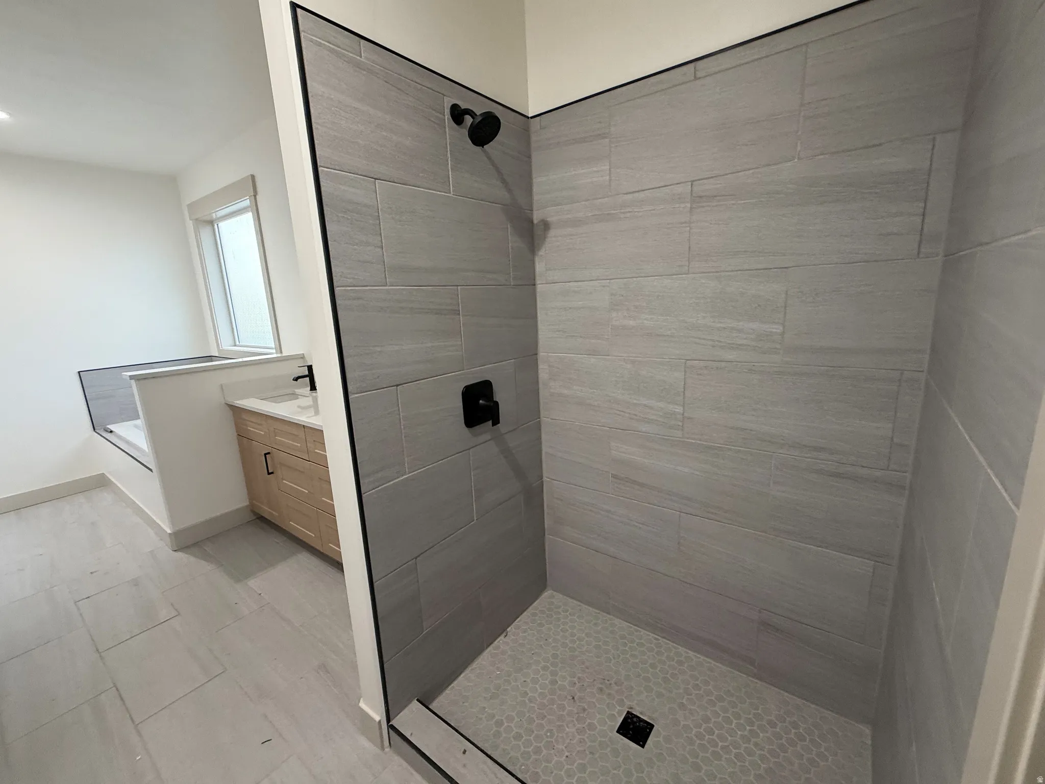 Walk-in shower with gray tile surround and hex tile floor