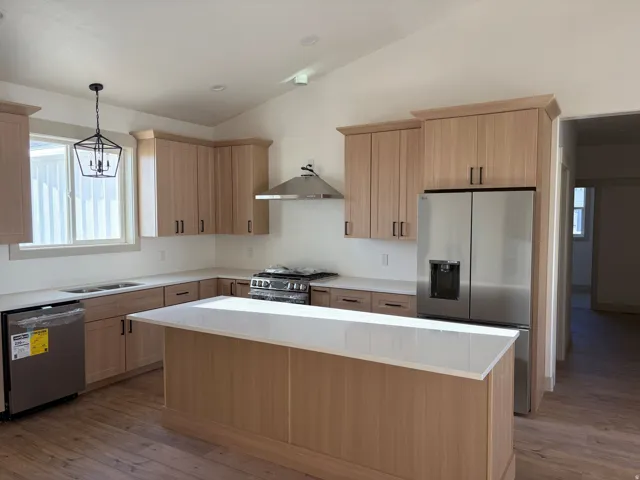 Kitchen featuring wood-finish cabinetry, stainless steel appliances, a center island with a white countertop, recessed lighting, and wood-finish flooring