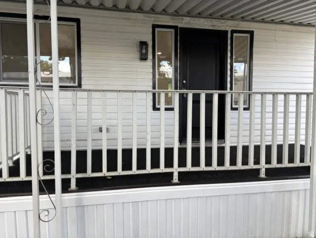Front entry with a dark door, adjacent sidelights, and exterior wall lantern