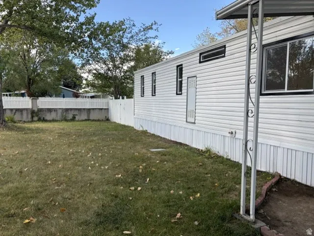 White vinyl siding exterior with black-trimmed windows, a white picket fence, and a grass-covered yard