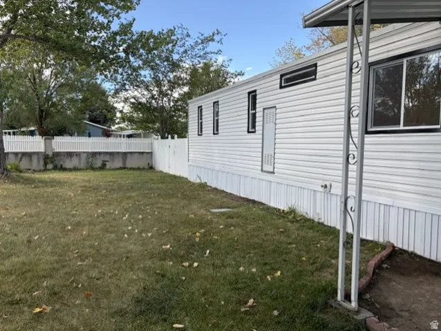 White vinyl siding exterior with black-trimmed windows, a white picket fence, and a grass-covered yard