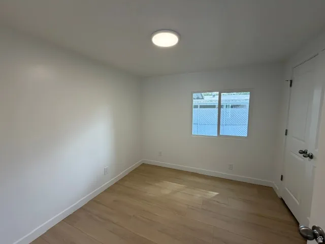 Wood-finish flooring, white walls, and a white ceiling with a flush-mount light fixture