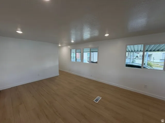 Recessed lighting, wood-finish flooring, white walls, multiple windows, and white trim