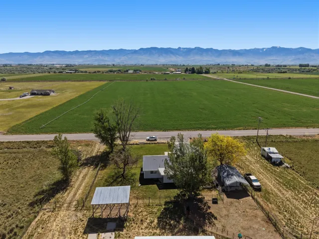 Expansive rural acreage with distant mountain scenery, lush green fields, and multiple outbuildings