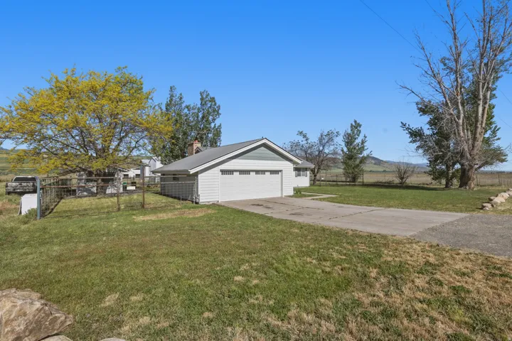 Attached two-car garage with white paneled door, light green gable, and a concrete driveway