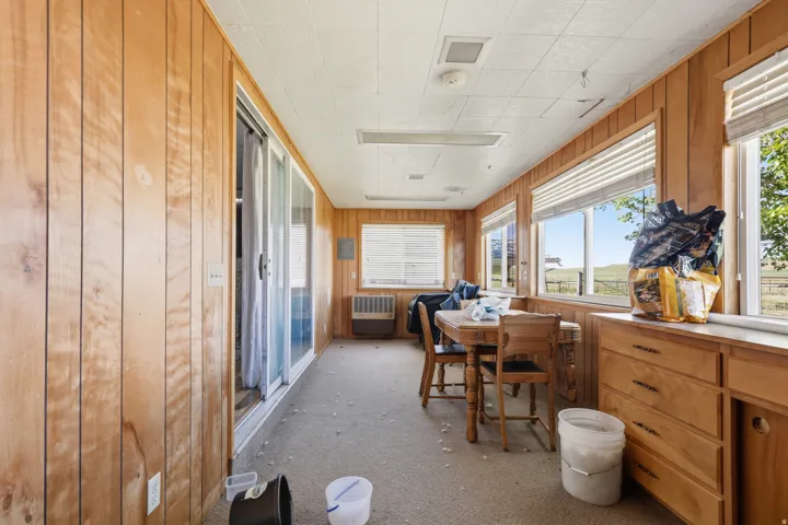 Wood paneling, multiple windows with blinds, sliding glass door, built-in cabinetry, and carpeted flooring