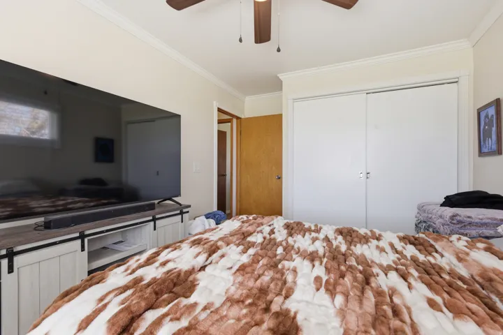 Crown molding, ceiling fan, sliding closet doors, and wood-finish door