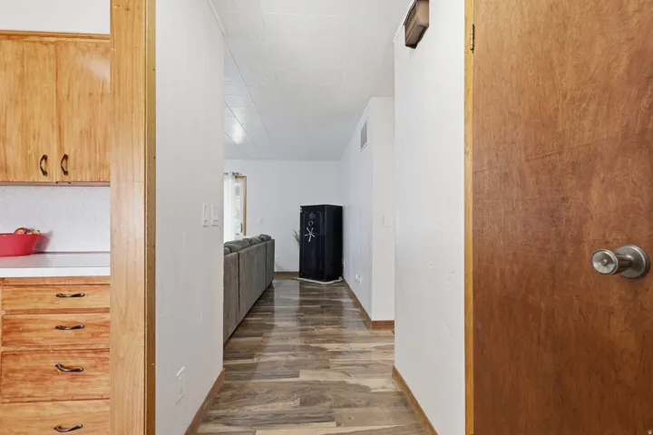 Wood-finish flooring throughout, white walls, and built-in wood cabinetry with dark hardware