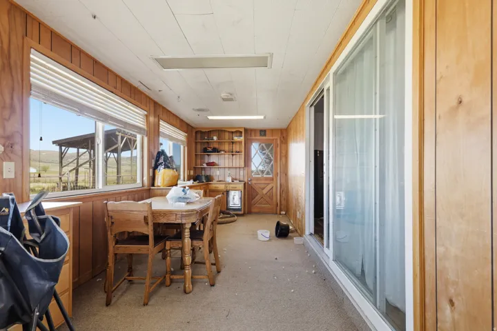 Wood-paneled room with multiple windows, built-in shelving, and a glass-paneled door