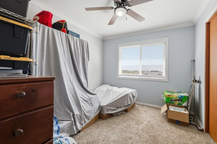 Window with blinds, ceiling fan with light fixture, light blue wall paint, crown molding, and wood-finish door