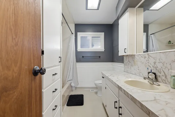 Bathroom vanity with a cream-colored sink, patterned countertop, and white cabinetry
