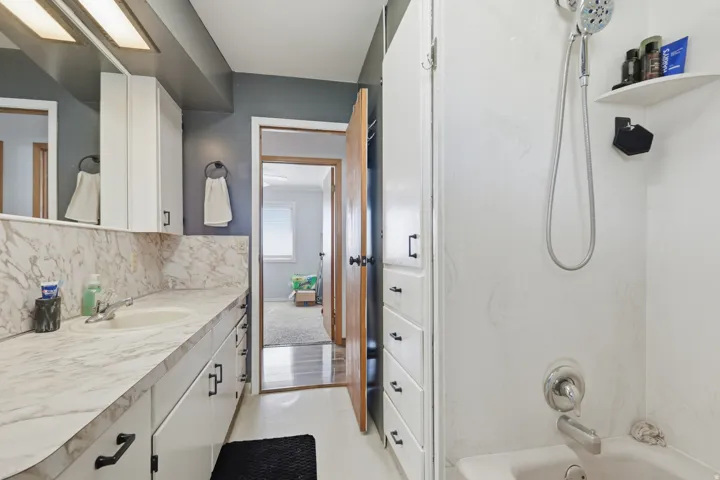 Vanity with integrated sink, white cabinetry, and a large mirror