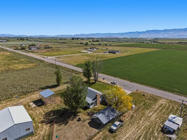 Property featuring multiple outbuildings, a paved road frontage, and expansive open fields