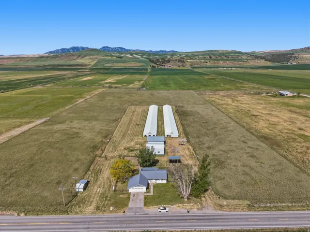 Expansive property featuring a single-story residence, two large outbuildings, a detached garage, and substantial open land