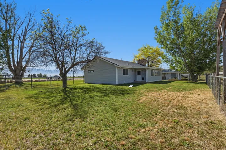 Expansive lot with a light gray siding exterior, a dark shingle roof, and mature trees