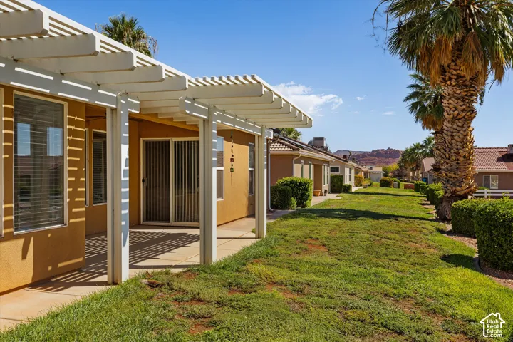 Outdoor patio with a white pergola, sliding glass door, and exterior stucco finish