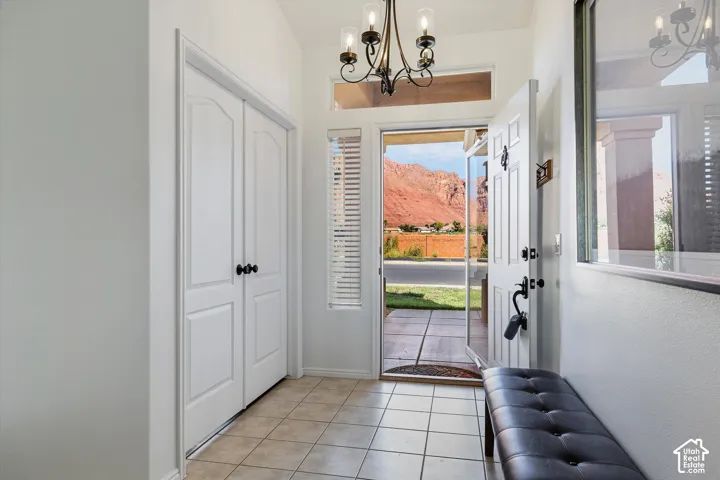 Entryway featuring a decorative chandelier, neutral tile flooring, and a window with blinds
