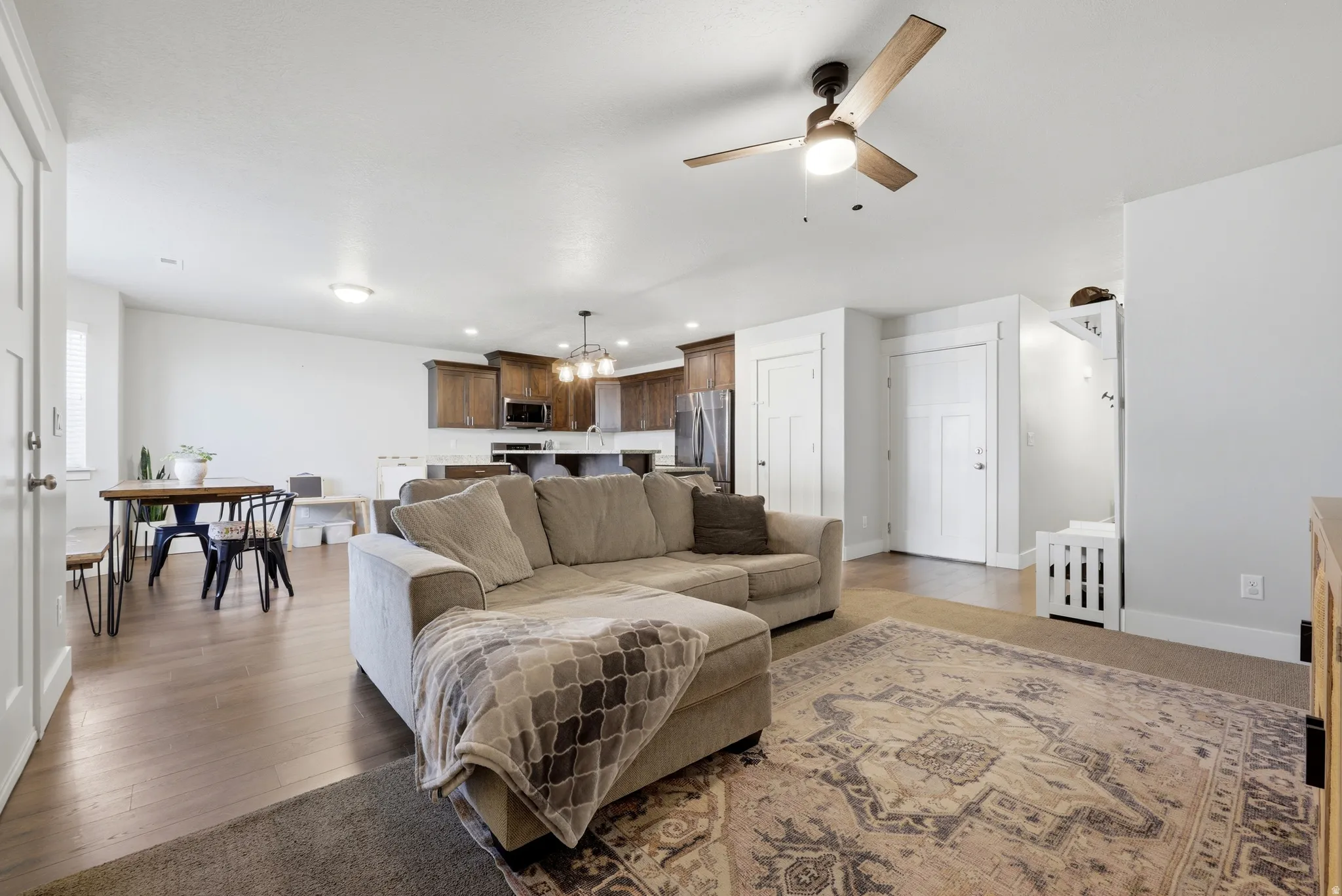 Hardwood-finish flooring, recessed lighting, ceiling fan, white paneled doors, and dark wood-finish cabinetry